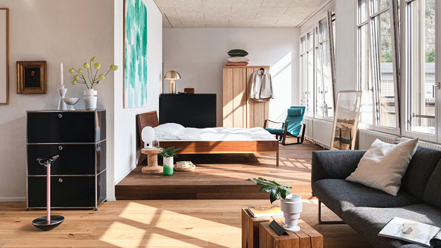 Unter den Möbeln und Wohnaccessoires sind zahlreiche Klassiker zu finden, wie beispielsweise der elegante Loungesessel von Jean Prouvé, der farblich zum grossen Bild über dem Bett passt.